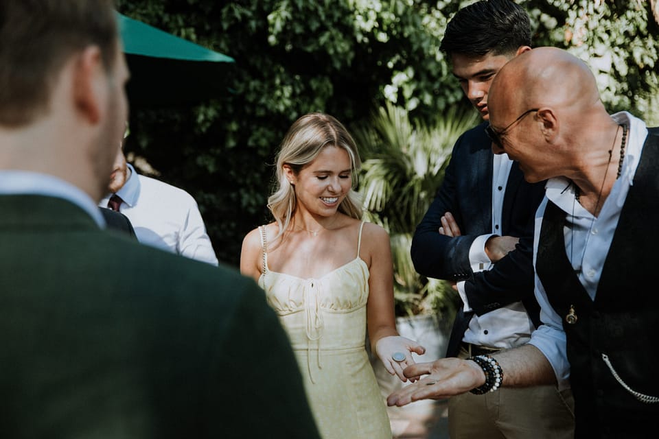 Roberto Forzoni, wedding entertainment, doing a coin effect to two summer wedding guests.